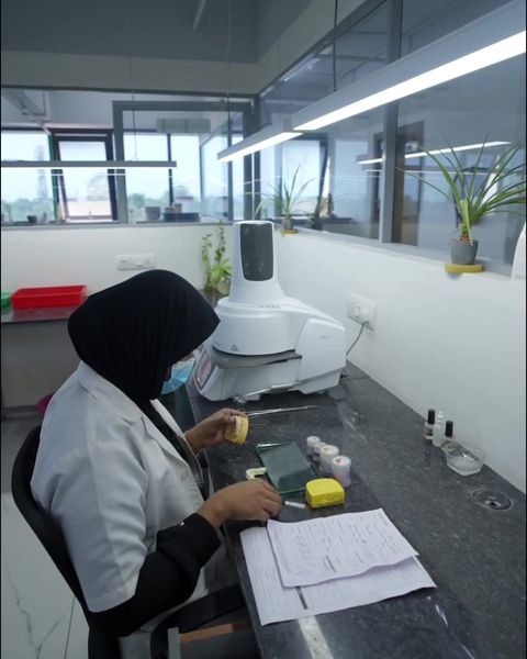 A technician at a bench beside a desktop model scanner