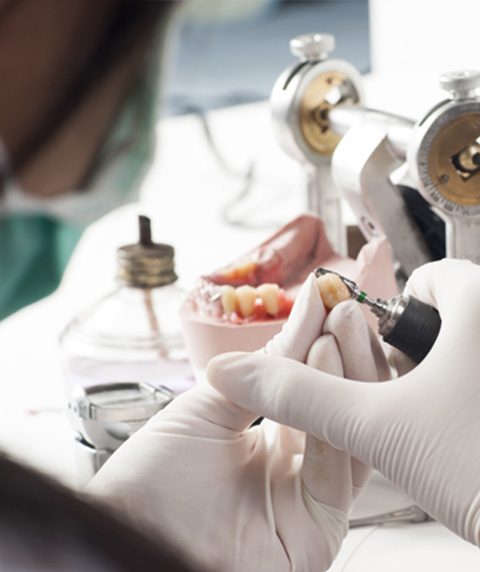 A dental technician working on a model at the lab bench